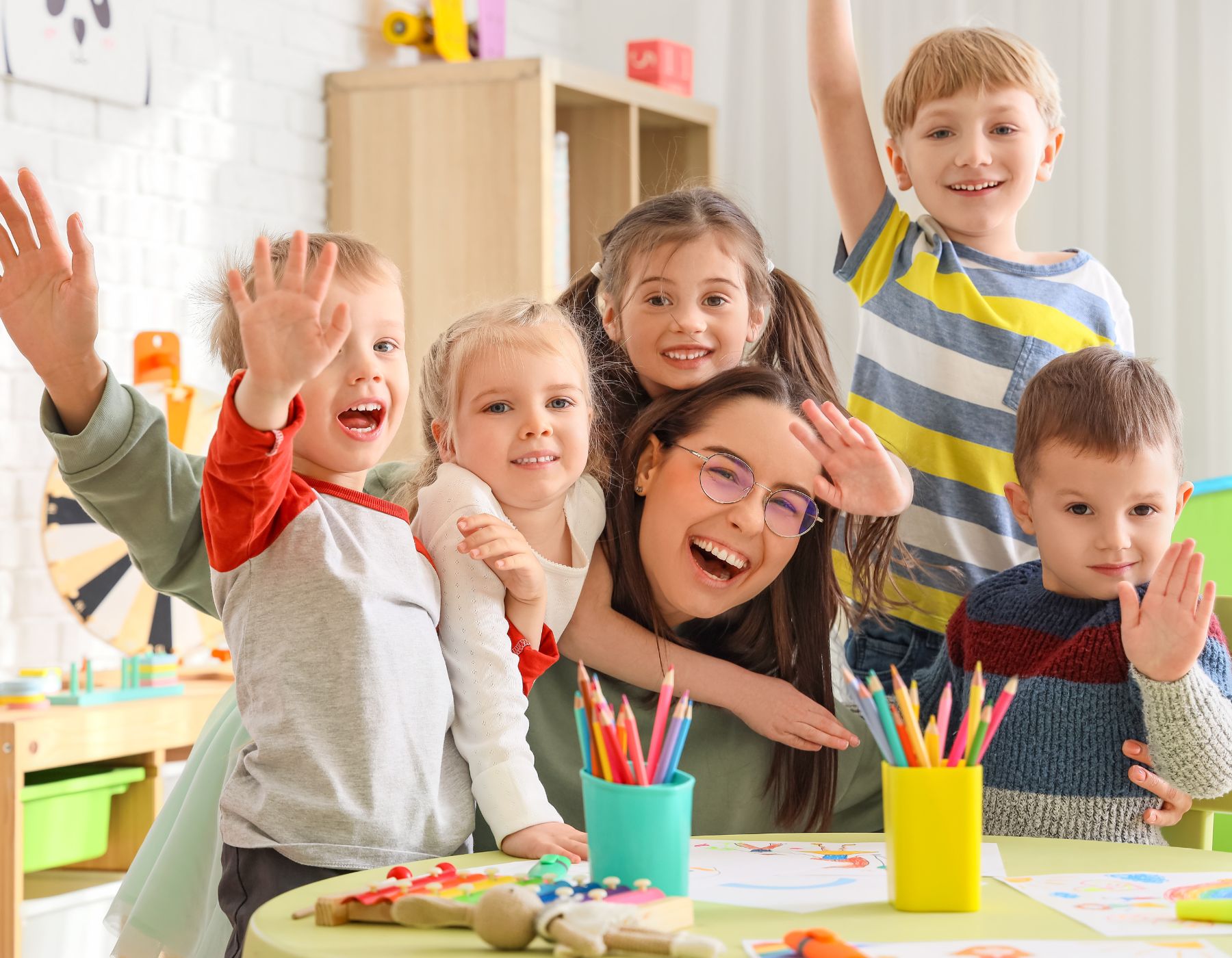 Alumnos de kínder y primaria junto a una profesora bilingüe del Instituto Víctor Hugo saludando con la mano en un taller lúdico del curso de verano de la Narvarte.